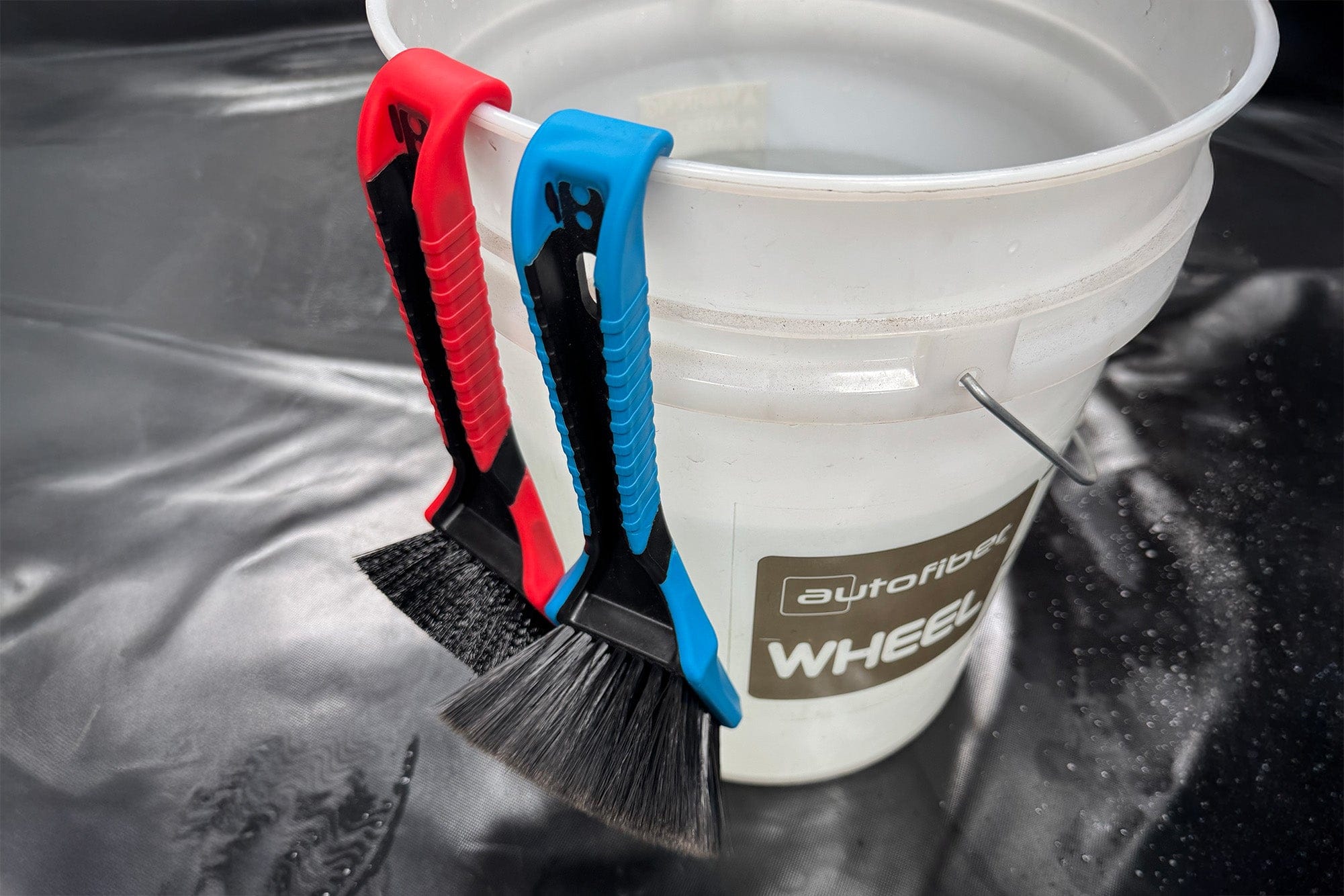 SKORP brushes hooked on the rim of a detailing bucket — hooks in action